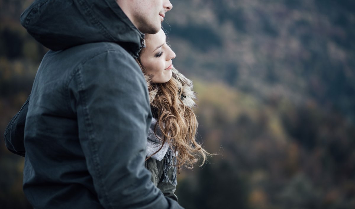 Mann und Frau stehen Arm in Arm auf einem Berg.
