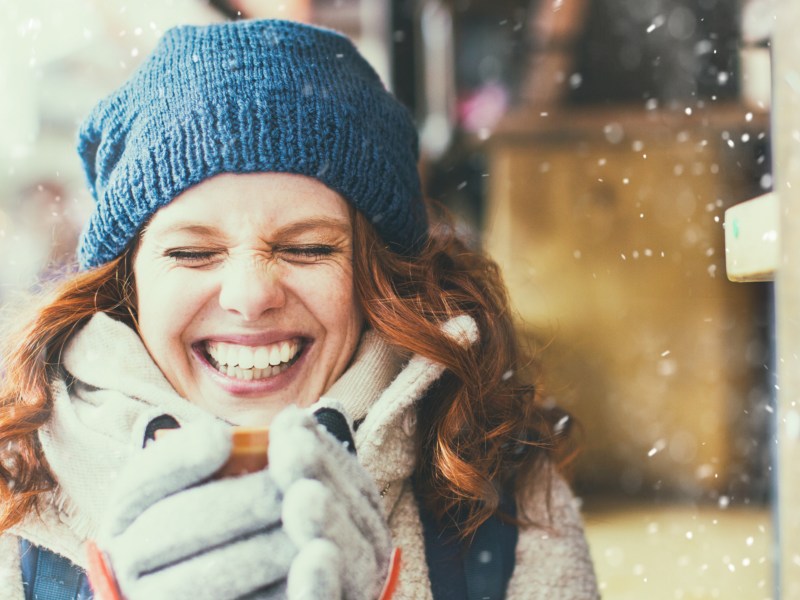 Rothaarige Frau mit einer Tasse in der Hand im Schnee.