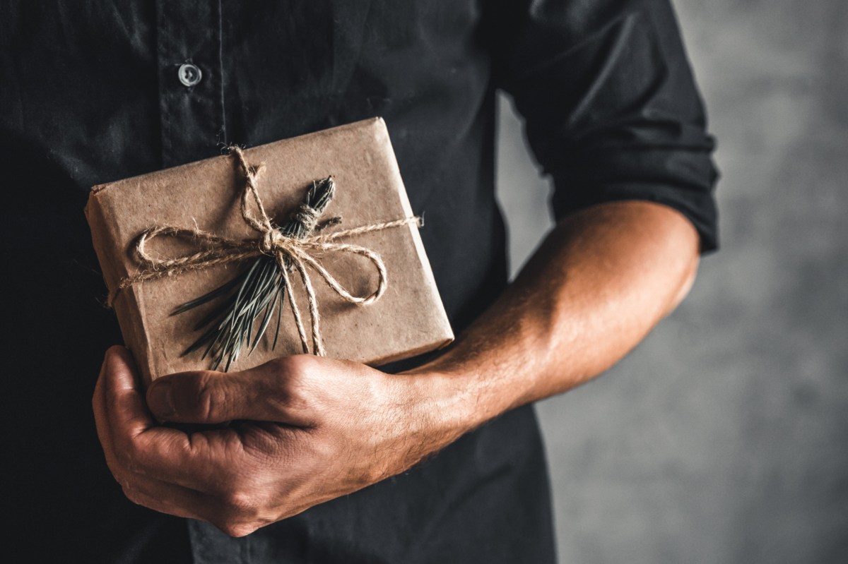 Mann hält ein Weihnachtsgeschenk in der Hand