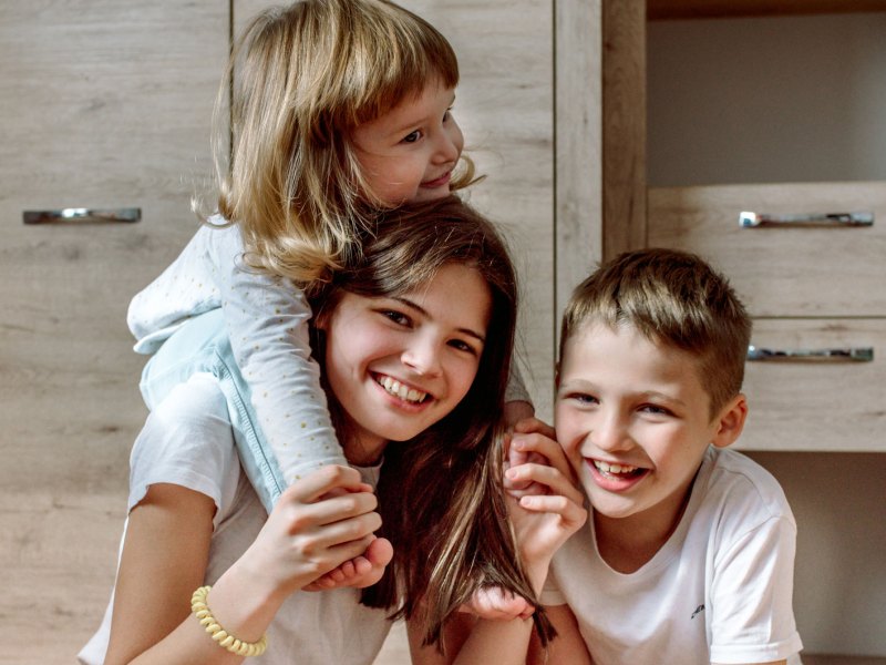 Große Schwester, mittlerer Bruder und kleinste Schwester spielen gemeinsam und haben Spaß.