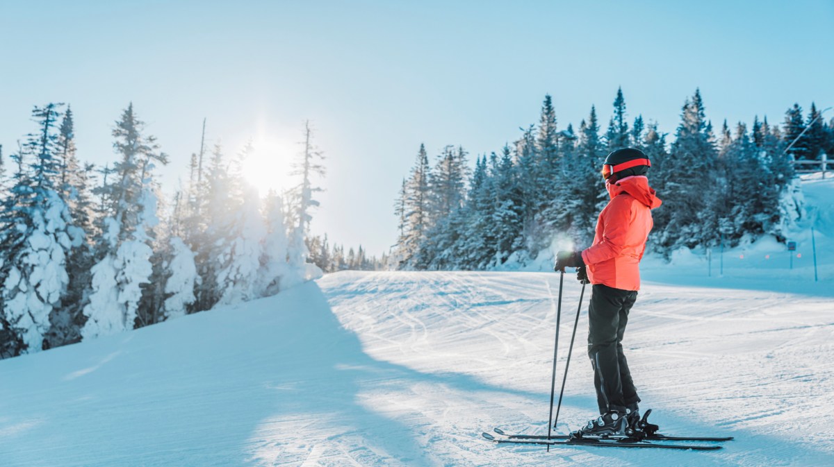 Frau mit Ski-Ausrüstung im Skigebiet bie Sonnenschein