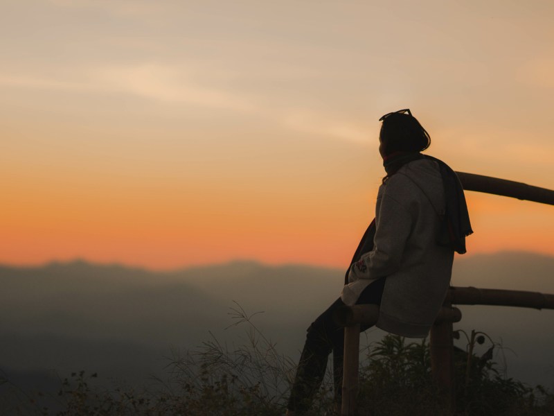 Frau auf einem Stein im Sonnenuntergang