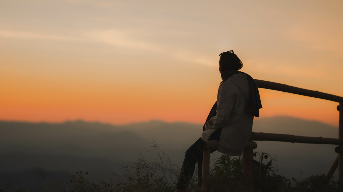 Frau auf einem Stein im Sonnenuntergang