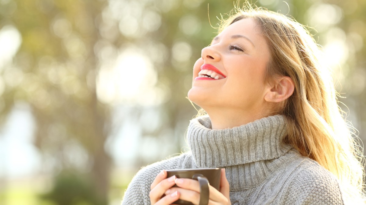 Frau mit Tasse in der Hand lächelt