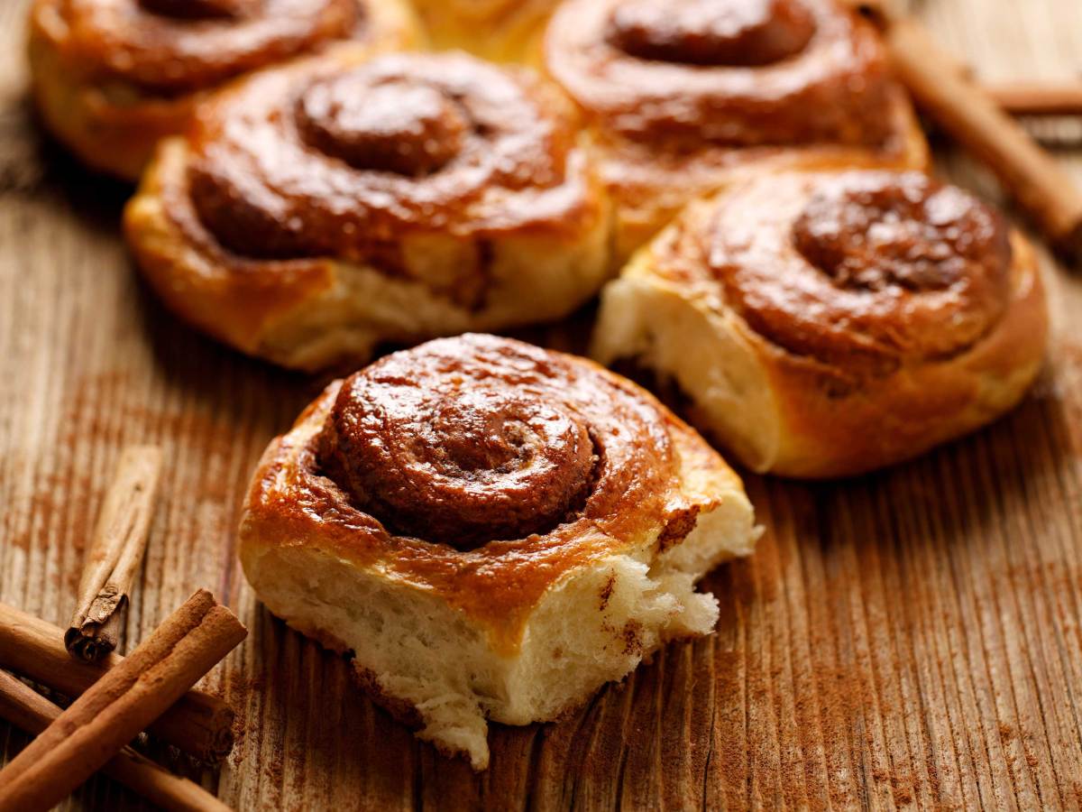 Traditionelle spiralf&ouml;rmige Zimtschnecken auf einem Holztisch, Nahaufnahme