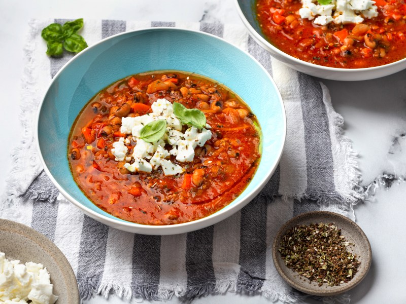 Gyros Suppe mit Deko in blauer Schüssel auf einem gestreiften Tuch