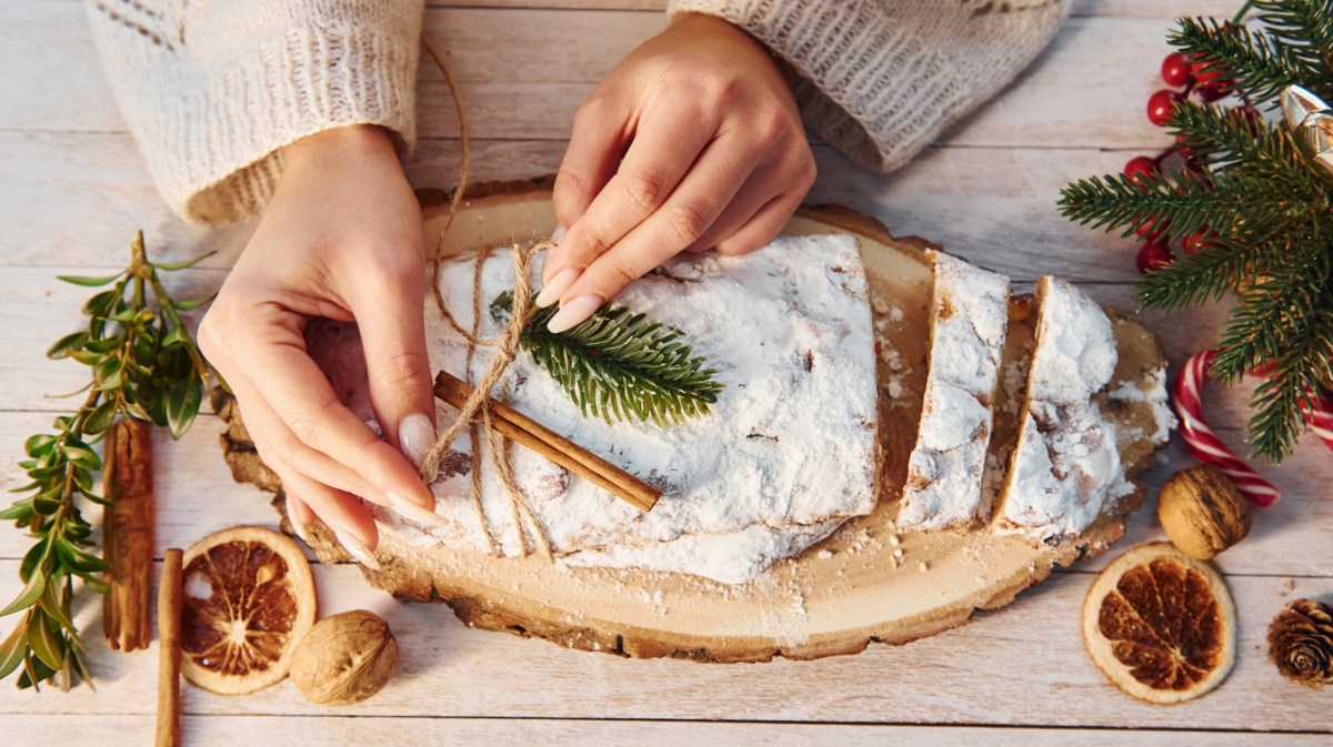 Frau dekoriert Stollen, der auf dem Weihnachtstisch steht