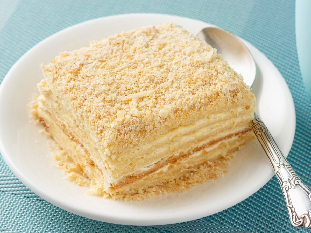 Kuchen mit vielen Cremeschichten auf einem wei&szlig;en Teller.