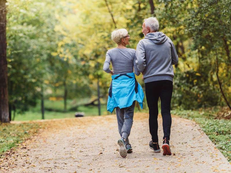 Fröhliches aktives Seniorenpaar beim Joggen im Park. Gemeinsam trainieren, um das Altern aufzuhalten.