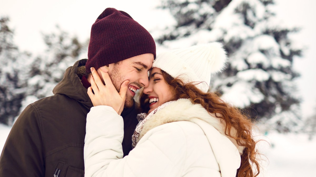 Frau und Mann küssen sich im Schnee.