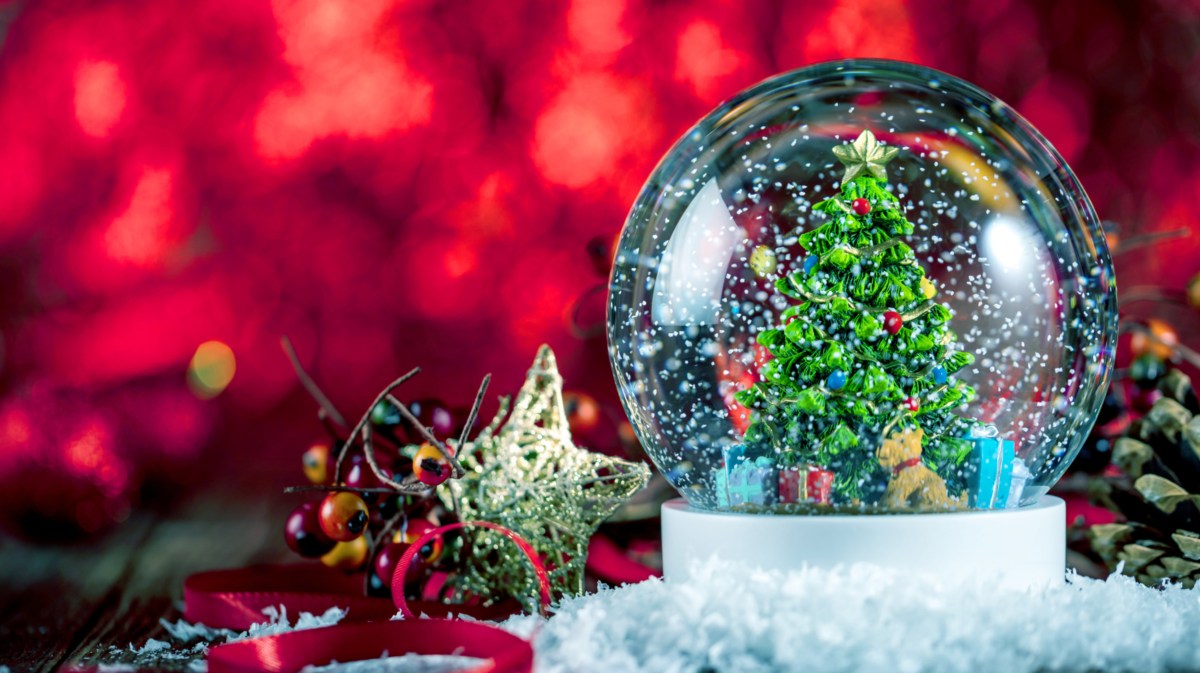 Eine Schneekugel mit einem Tannenbaum und Weihnachtsdeko auf einem Tisch dekoriert