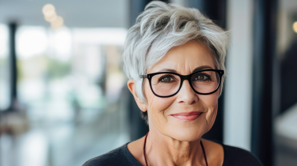 Ältere Frau mit Brille sitzt im Job.