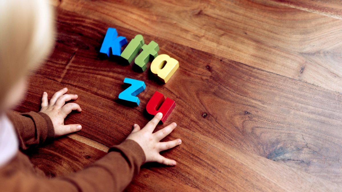 Schriftzug 'Kita zu' auf einem Holzboden.