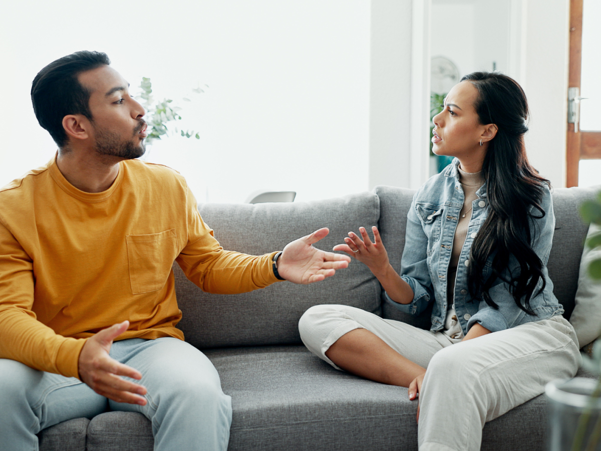 Frau und Mann auf Sofa, die sich gegenseitig Vorwürfe machen
