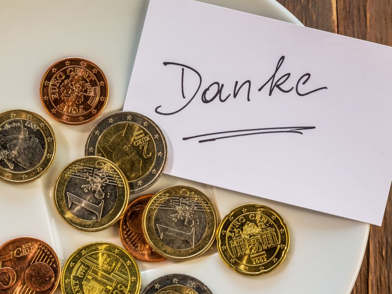 Münzgeld auf einem Teller mit einem Schild mit "Danke".