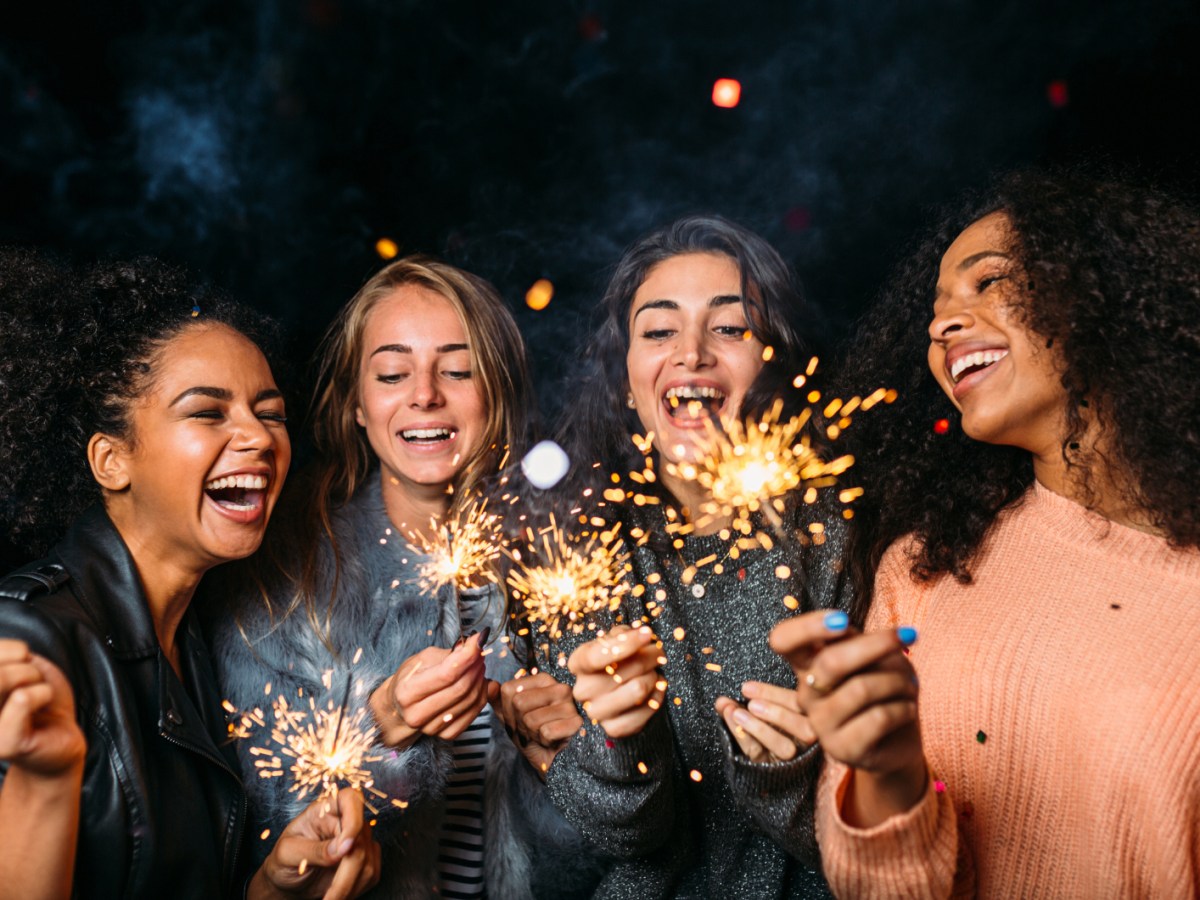 Vier junge Frauen haben Wunderkerzen angezündet.