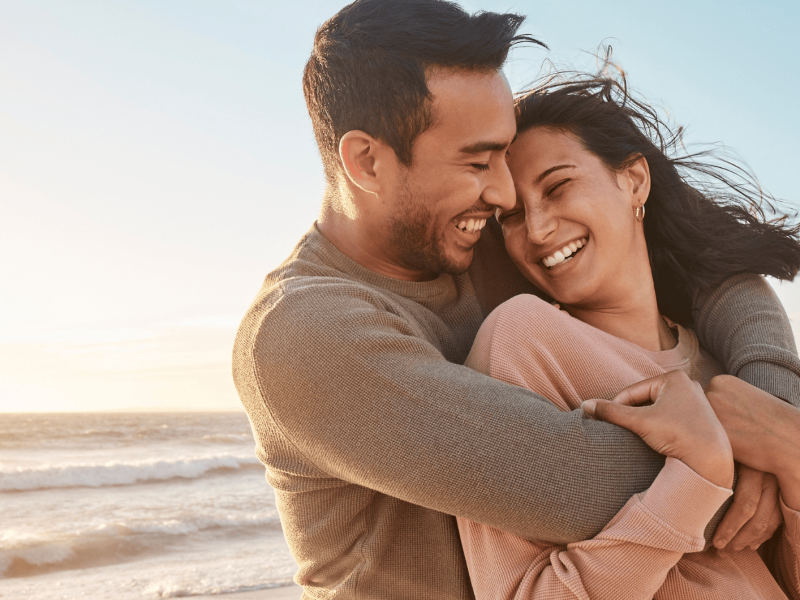 Glückliches Paar umarmt sich am Strand.