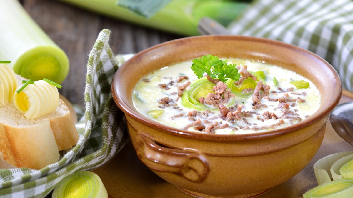 Käse-Lauch-Suppe mit Hackfleisch in braunem Keramiktopf.