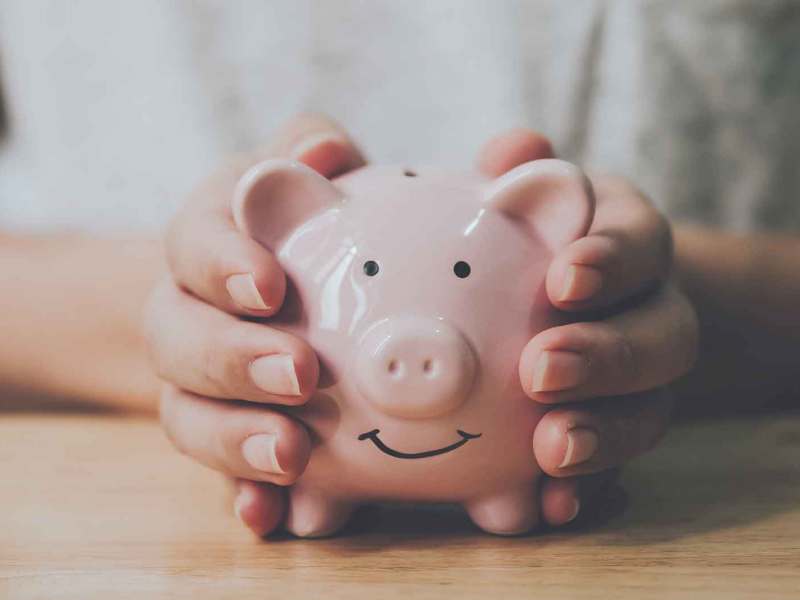 Junge Frau h&auml;lt ein rosa Sparschwein in beiden H&auml;nden.