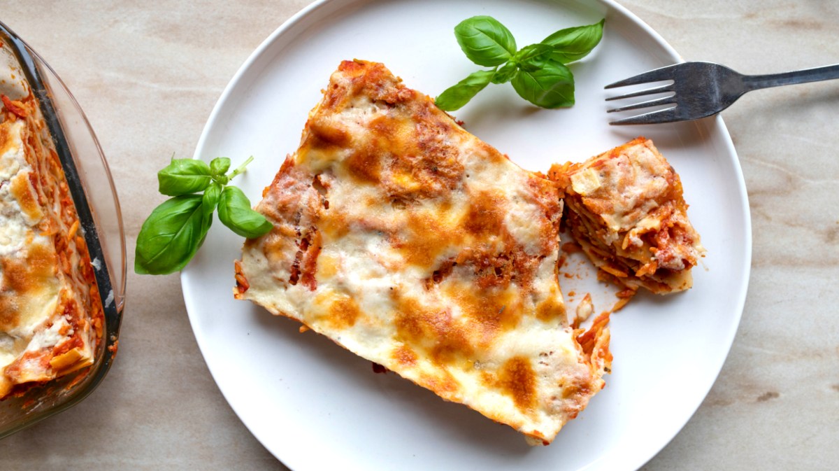 Vegetarische Gemüselasagne, ein Stück auf weißem Teller.