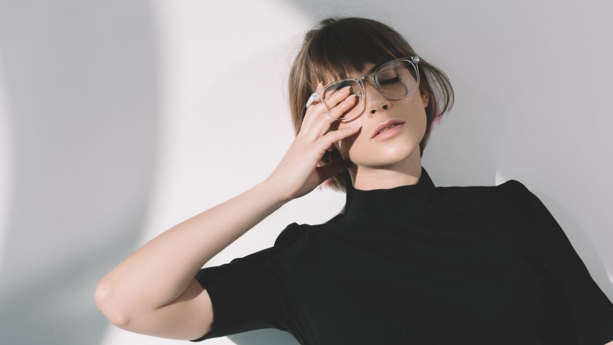 Frau mit Brille hält sich ein Auge zu, Symbolbild für introvertiert sein