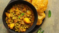 Kartoffelcurry in einer schwarzen Schale mit Brot angerichtet