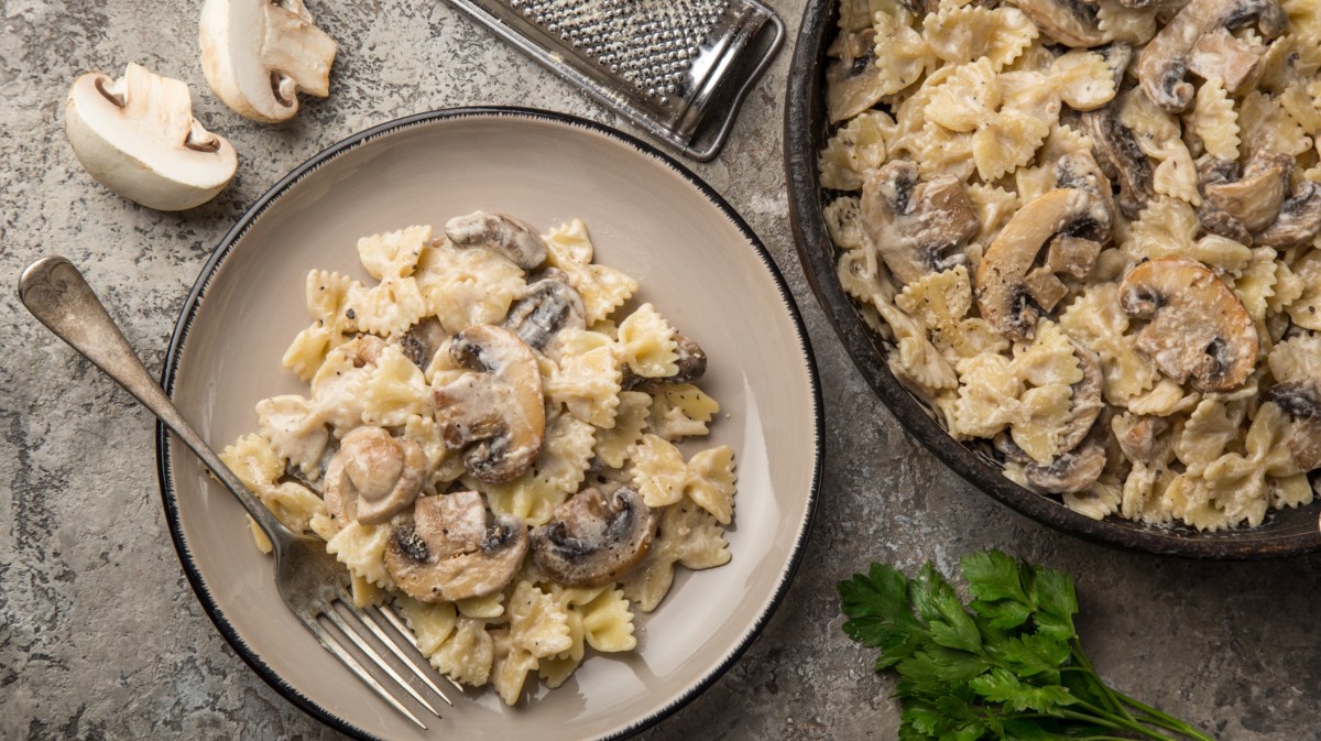 Nudelpfanne mit Pilzen und Sahnesoße auf tiefem Teller.