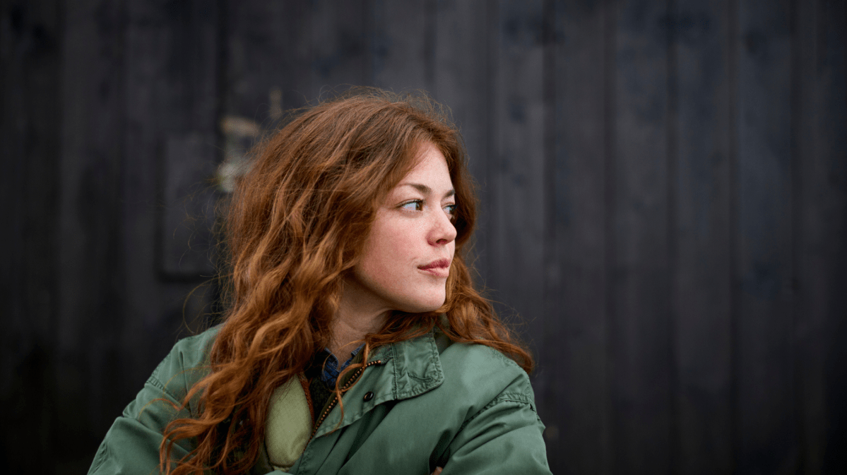 Frau mit roten Haaren blickt ernst zur Seite