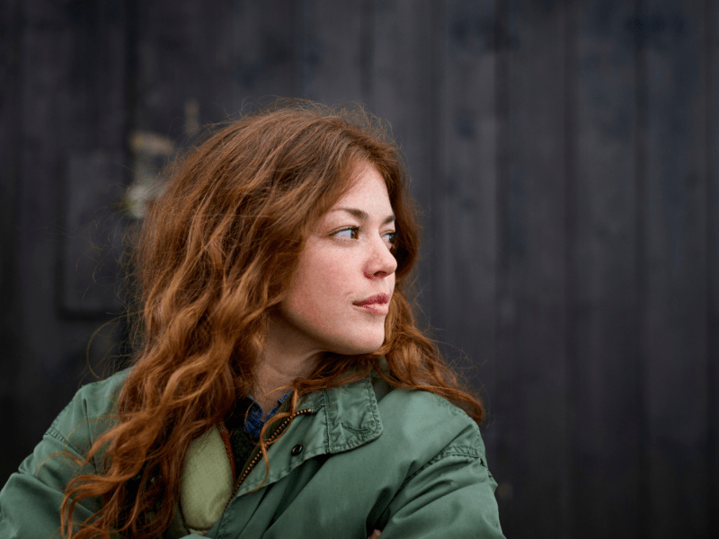 Frau mit roten Haaren blickt ernst zur Seite