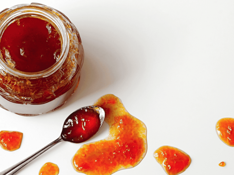 Offenes Marmeladenglas und Marmelade auf einem Löffel