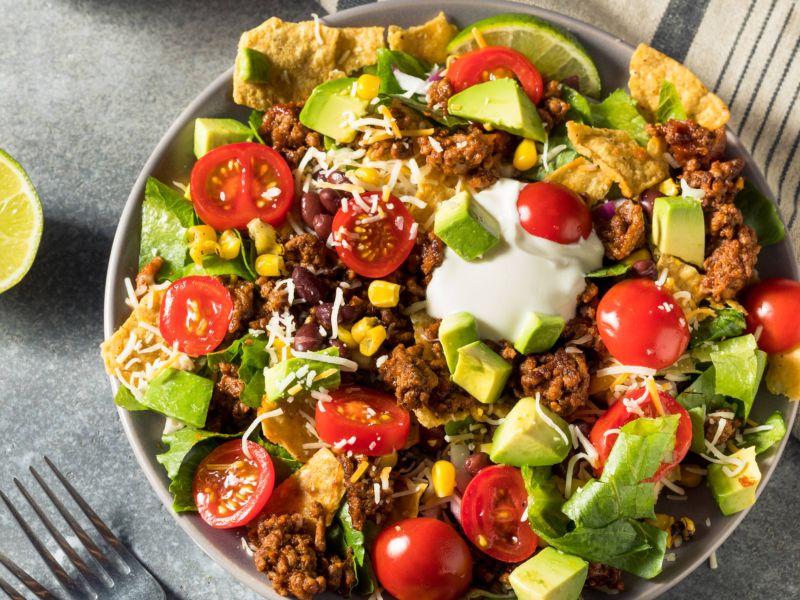 Salat mit Hackfleisch, Tomaten, Avocado und Limette.