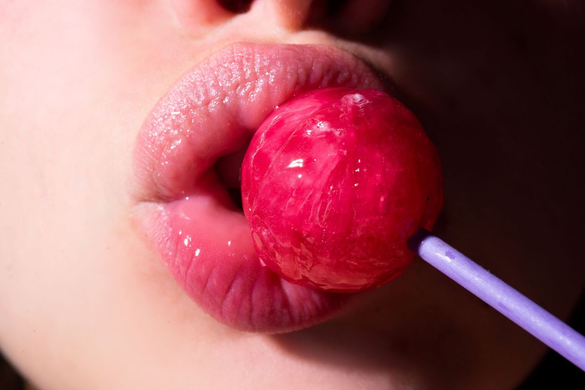 Lippen umschließen einen pinken Lolli als Symbolbild für einen Blowjob