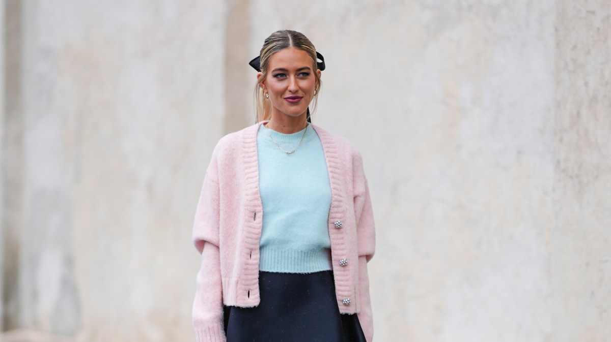 Emili Sindlev in einem rosa-verspielten Cardigan mit Schleife im Haar