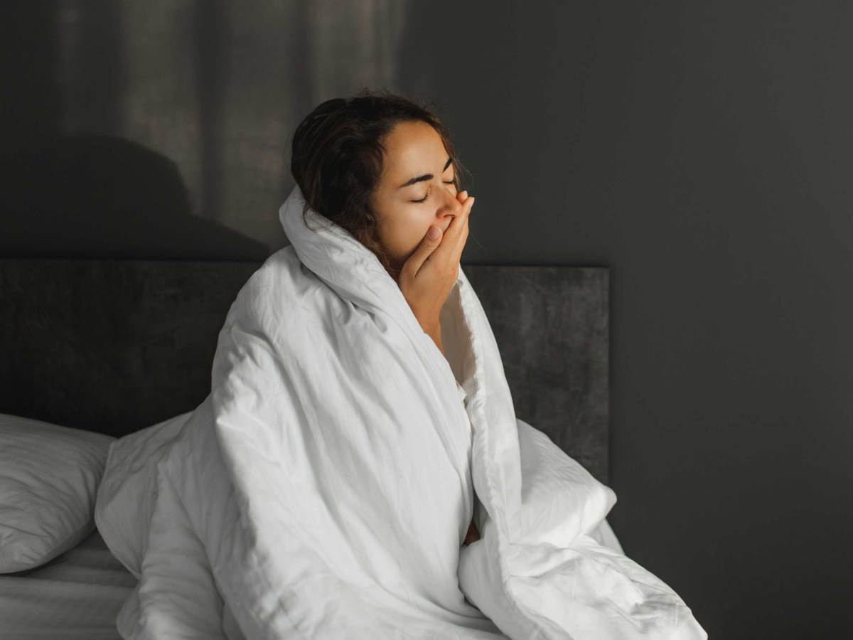 Eine m&uuml;de Frau hat nicht genug Schlaf bekommen. Schlaflosigkeit in der Nacht und psychische Gesundheit. Sch&ouml;nes Morgenlicht im Schlafzimmer.