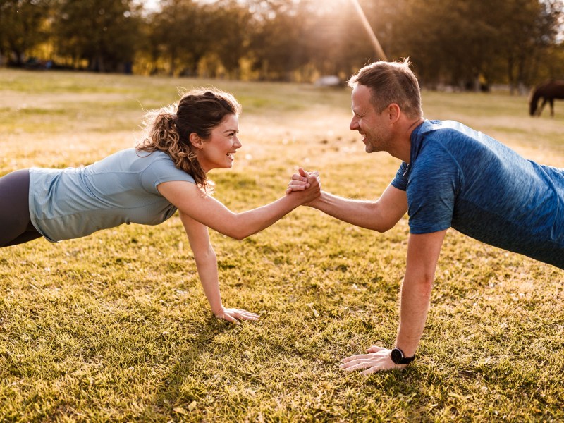 Als Paar abnehmen: Frau und Mann reichen sich während Plank Hand