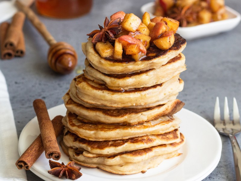 Pancakes auf einem weißen Teller mit Apfelkompott obendrauf.