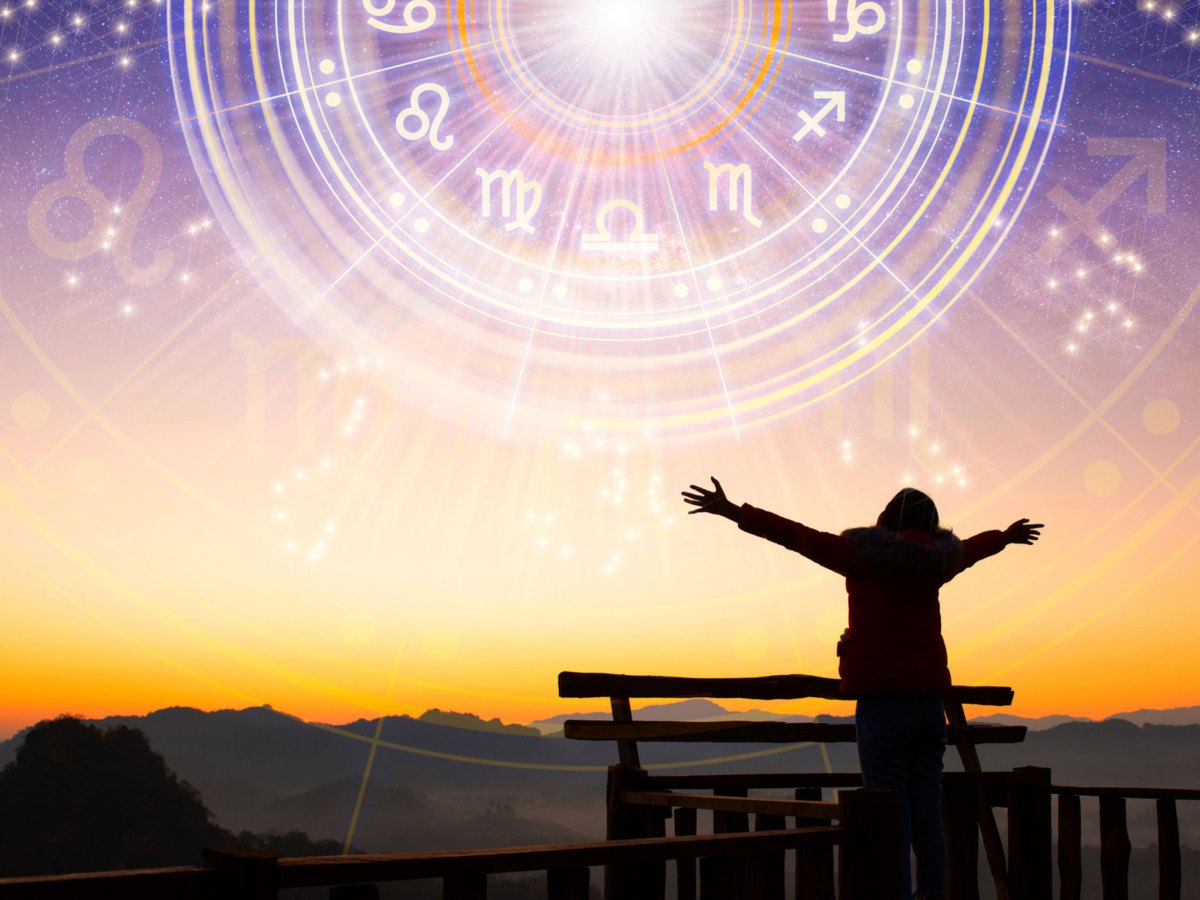 Frau mit ausgestreckten Armen bei Sonnenuntergang. Tierkreiszeichensymbol über das Bild gelegt als Symbolbild für das Wochenhoroskop