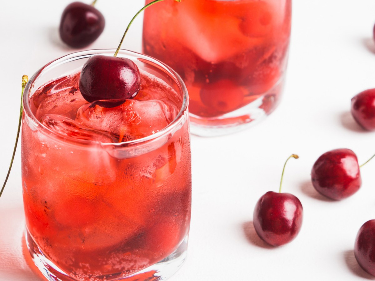 Roter Cocktail mit Eisw&uuml;rfeln und Kirschen.