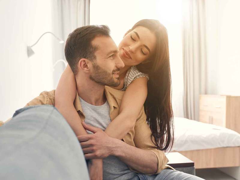 Verliebtes Paar sitzt auf der Couch. Sie umarmt ihn.