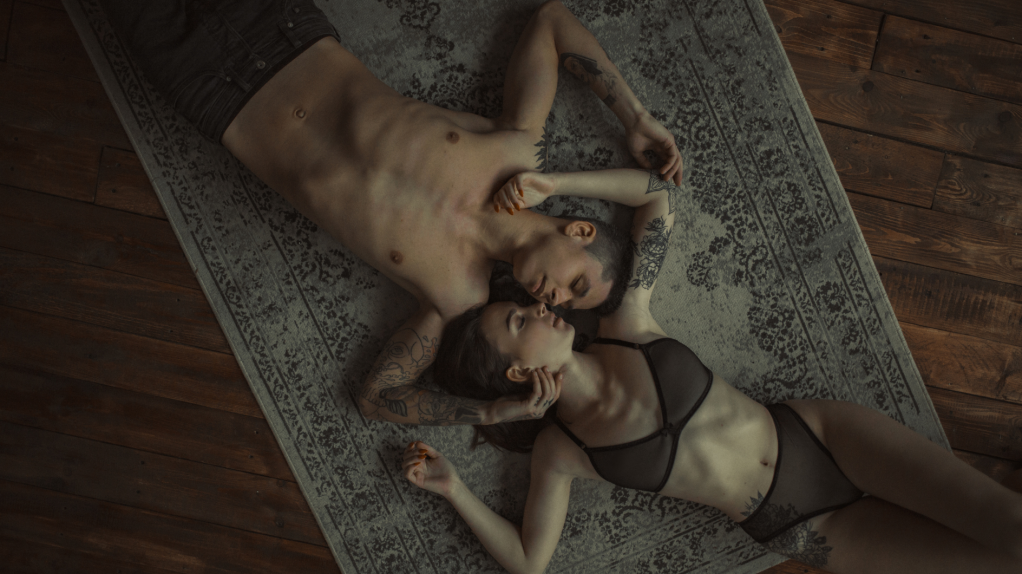 Ein Mann, der oberk&ouml;rperfrei auf einem Teppich mit einer Frau im BH liegt