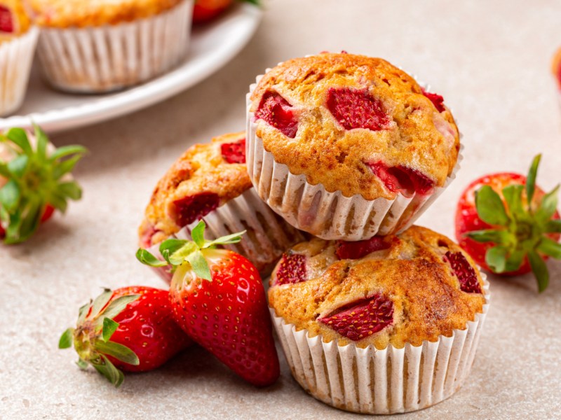 Mehrere Erdbeer-Muffins auf einem weißen Tisch.