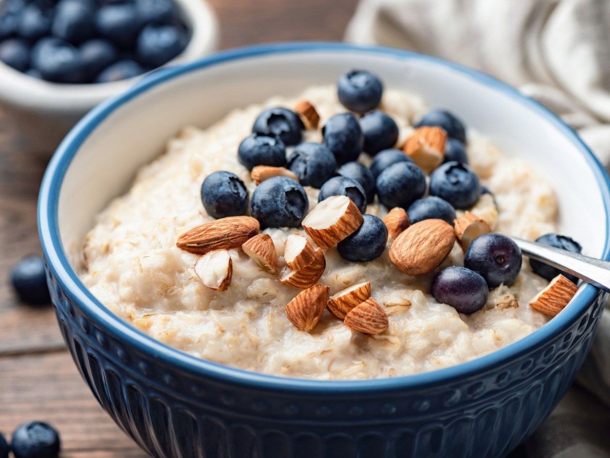 Porridge mit Blaubeeren und Mandeln in einer blauen Sch&uuml;ssel.