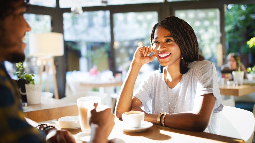 Frau in einem Café, die mit einem mann am Tisch sitzt.