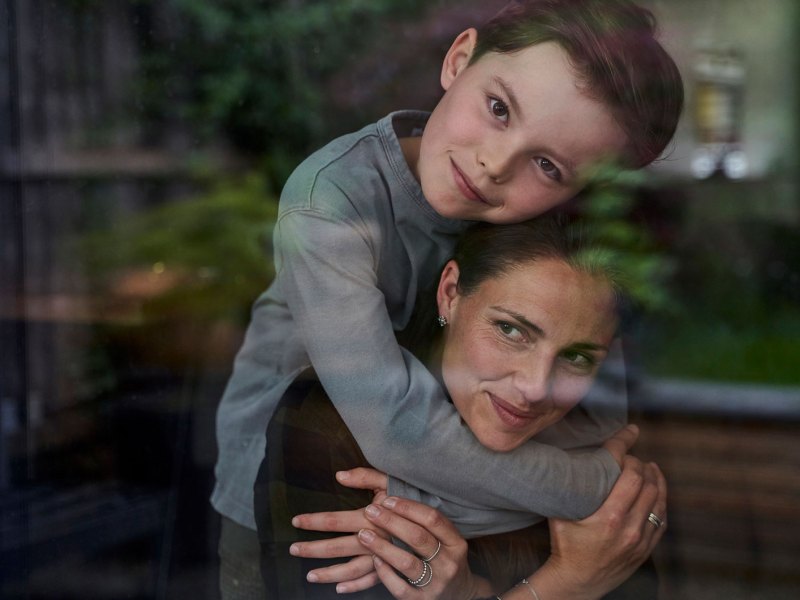 Ein Kind umarmt seine Mutter von hinten