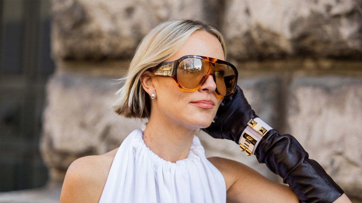 Frau im androgynen Look mit Sonnenbrille und kurzer Bob-Frisur.