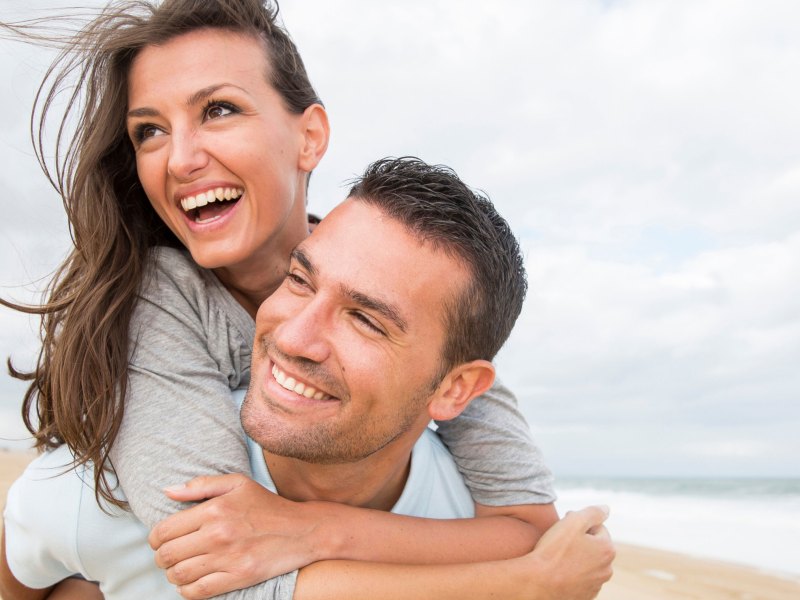 Mann trägt Frau auf dem Rücken und beide lächeln