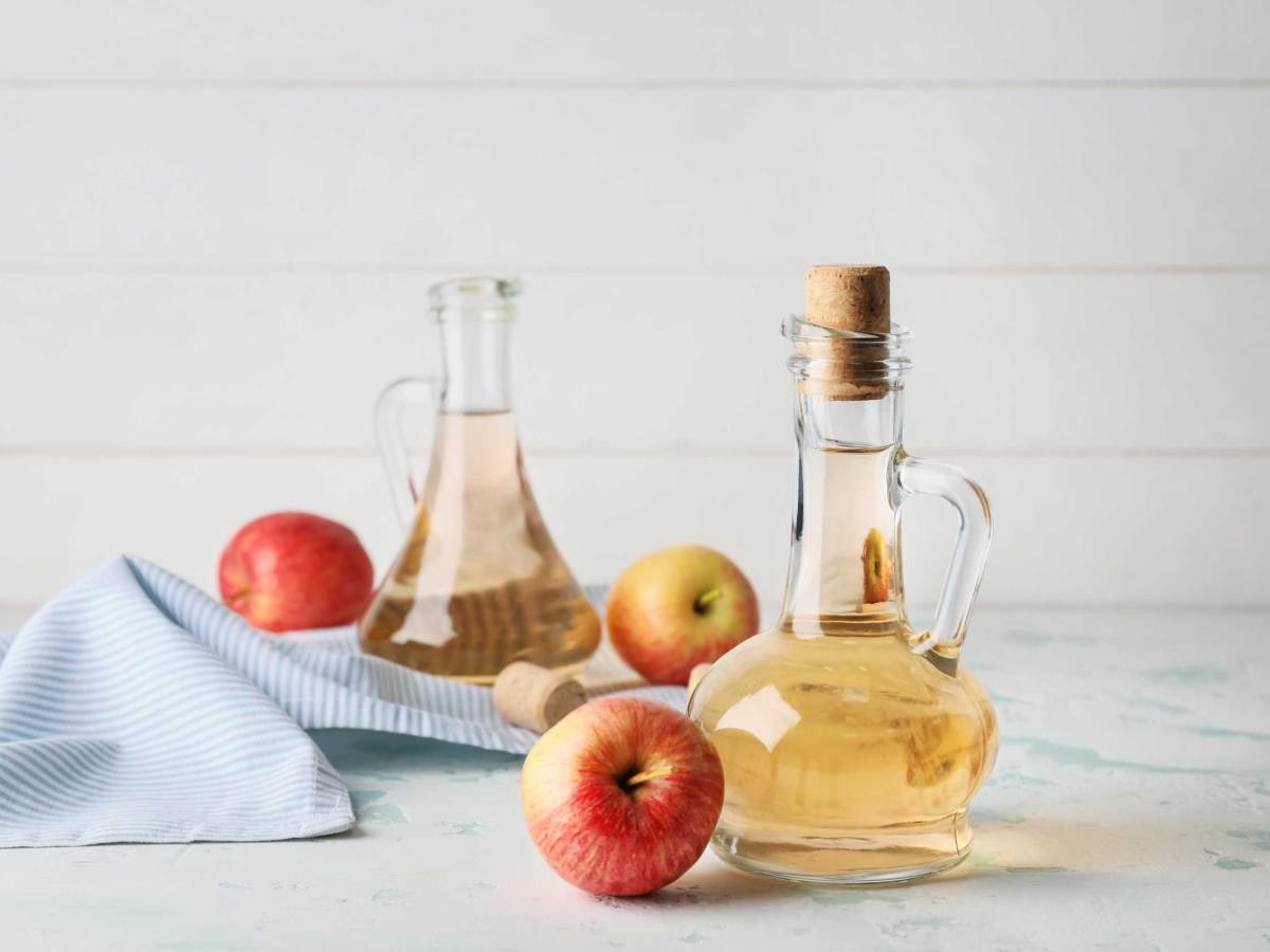 Flaschen mit Apfelessig auf wei&szlig;em Tisch