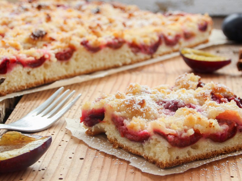 Pflaumenkuchen vom Blech auf einem Stück Backpapier.