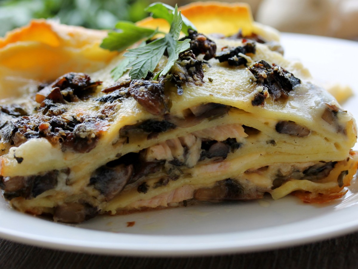 St&uuml;ck Pilz-Lasagne auf einem wei&szlig;en Teller.