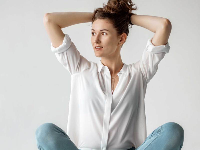 Junge Frau in weißem Hemd auf weißem Hintergrund. Attraktives Mädchen in weißer Kleidung auf weißem Hintergrund. Studioaufnahme.